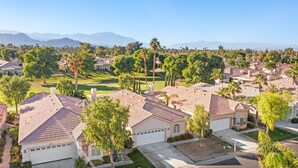 A residential area with houses featuring red-tiled roofs, surrounded by greenery and palm trees. - Golf-View Home | Indian Palms Resort Pool & Patio (Indio)