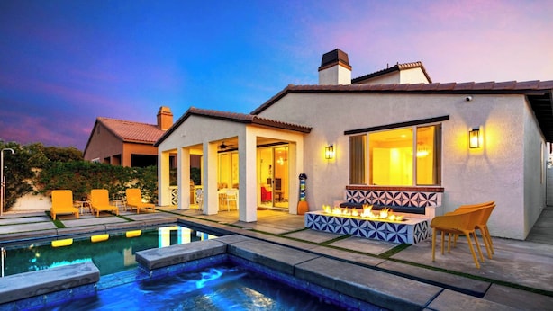Una casa moderna con piscina, mobiliario exterior y una zona de fuego.
