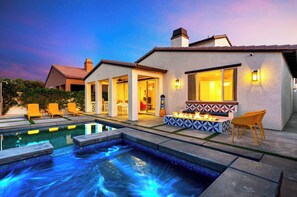 Une maison moderne dotée d’une piscine, d’un espace salon extérieur et d’un foyer.