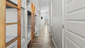 A narrow hallway with bunk beds on one side and a white door on the other. - Cozy home with Harbor Bridge & Ocean views. Close to Beach (Corpus Christi)