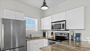 A modern kitchen with white cabinets, stainless steel appliances, and a granite countertop. - Cozy home with Harbor Bridge & Ocean views. Close to Beach (Corpus Christi)