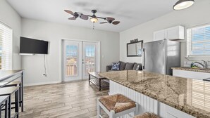 A modern kitchen with a large island, a ceiling fan, and a flat-screen TV. - Cozy home with Harbor Bridge & Ocean views. Close to Beach (Corpus Christi)
