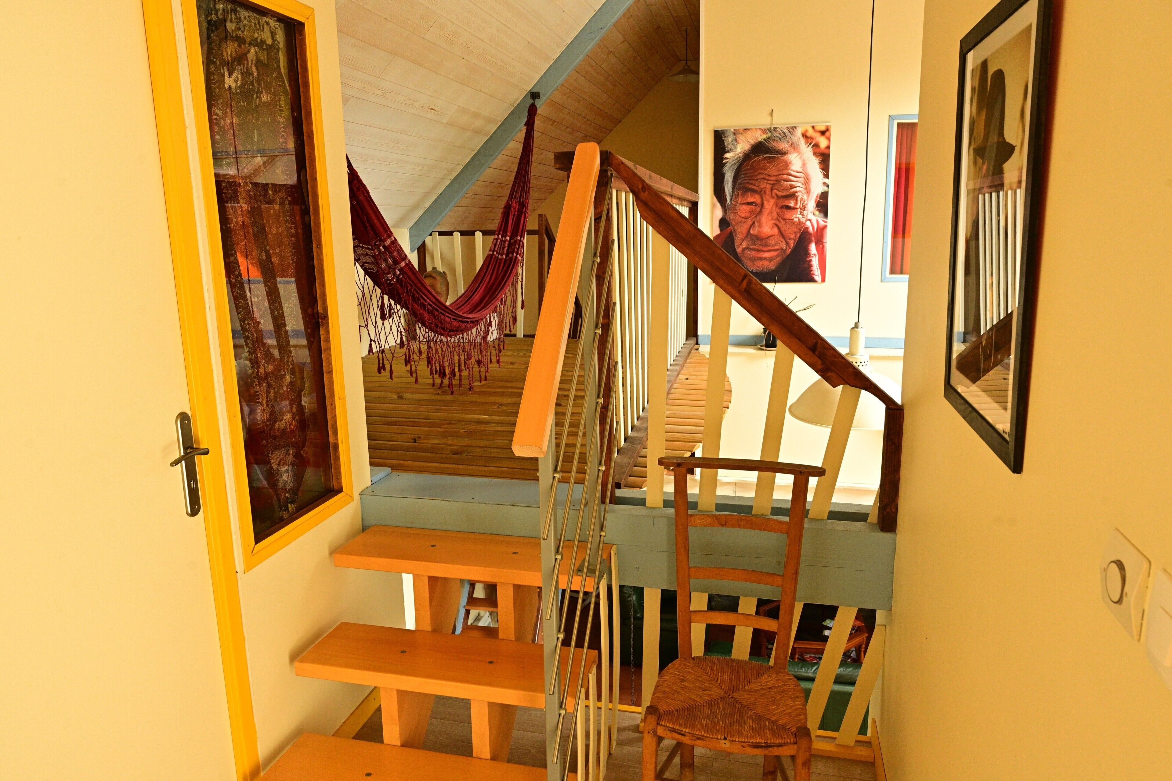Een houten trap met een hangmat, houten banken en een stoel.