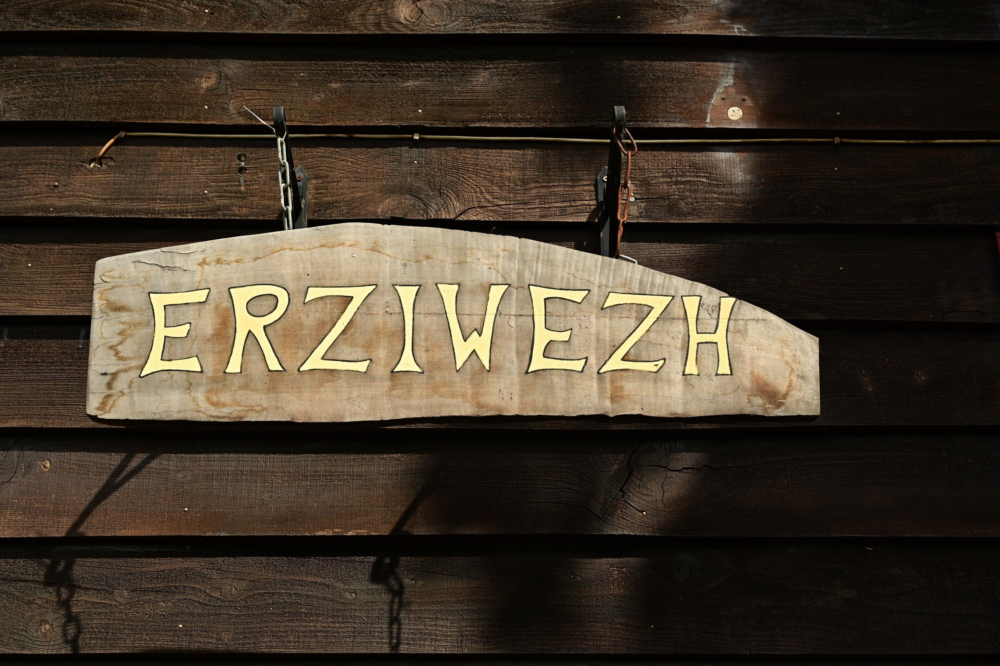 Une enseigne en bois portant le nom « ERZWEZH », fixée à un mur en bois.