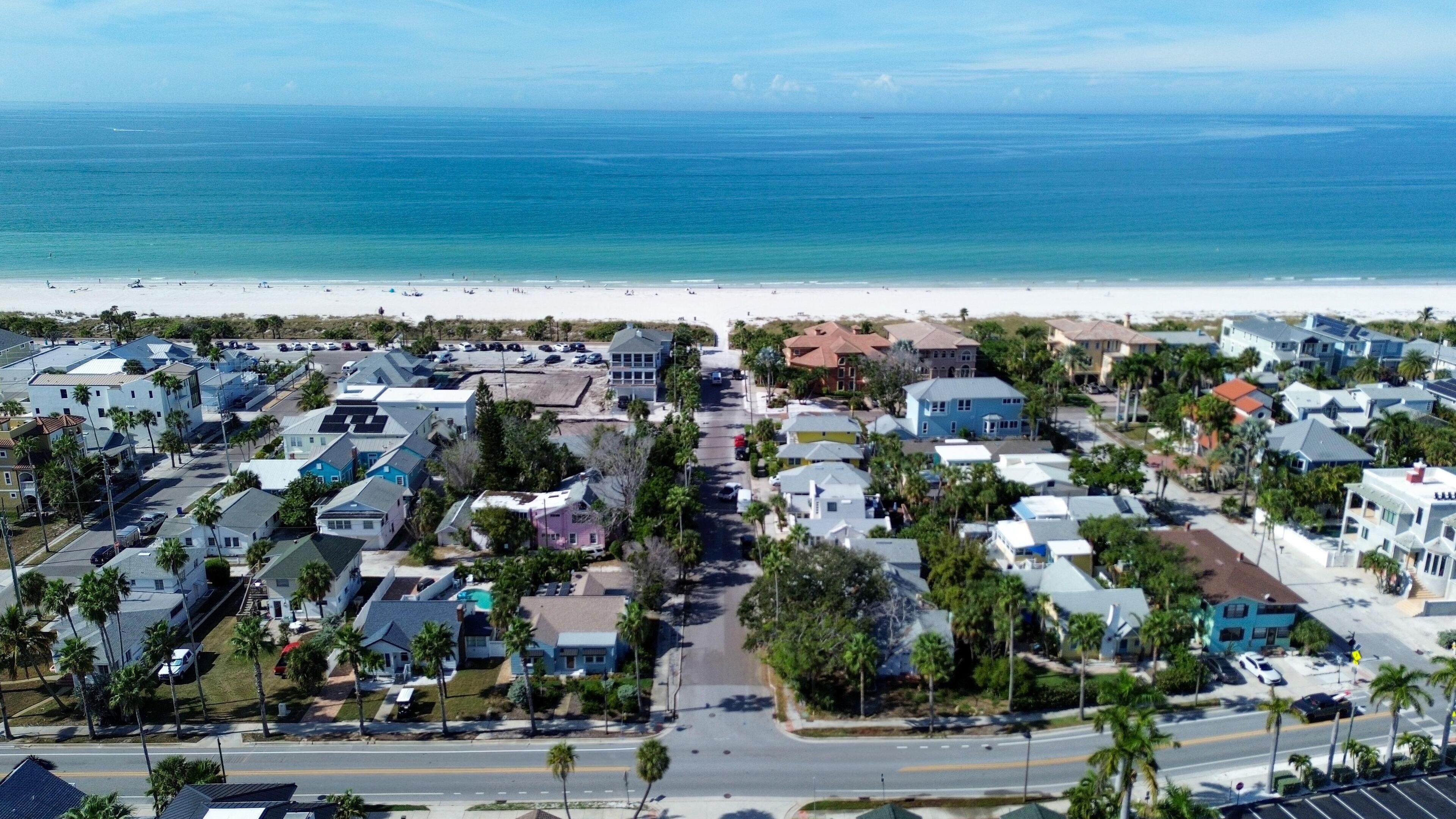 A coastal residential area with houses, a road, and a beach.