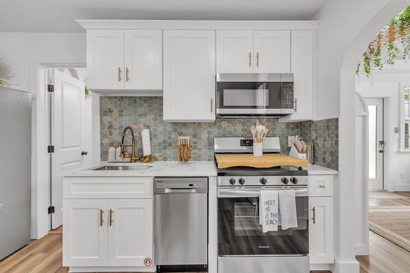 A modern kitchen with white cabinetry, a stainless steel dishwasher, a built-in oven, and a microwave. - La Barra #103 (St. Pete Beach)