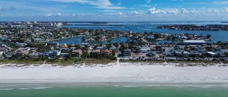 A coastal town with residential buildings, a beach, and a bridge in the distance.
