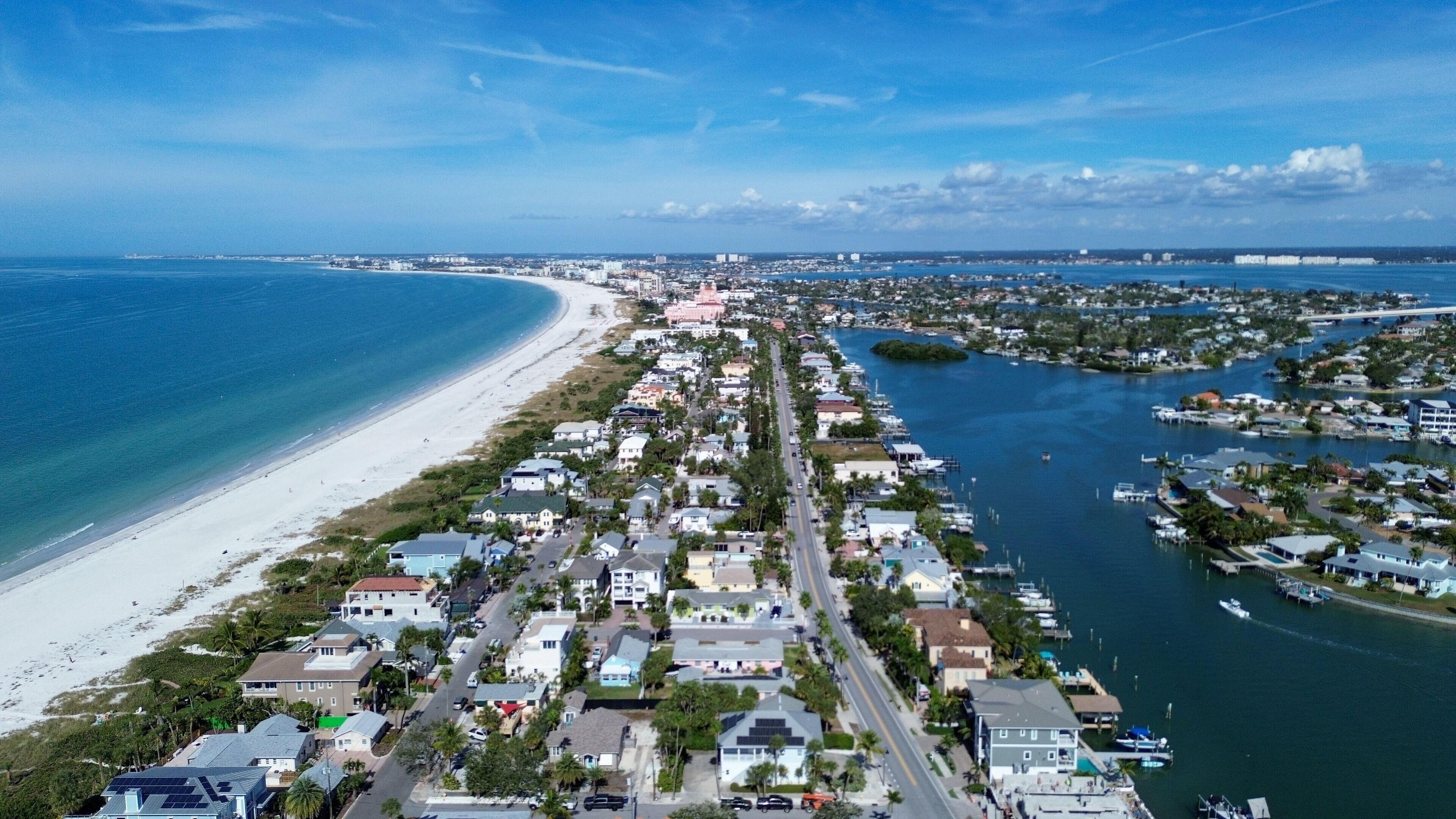 A coastal town with a long beachfront, dense residential area, and a marina with boats.