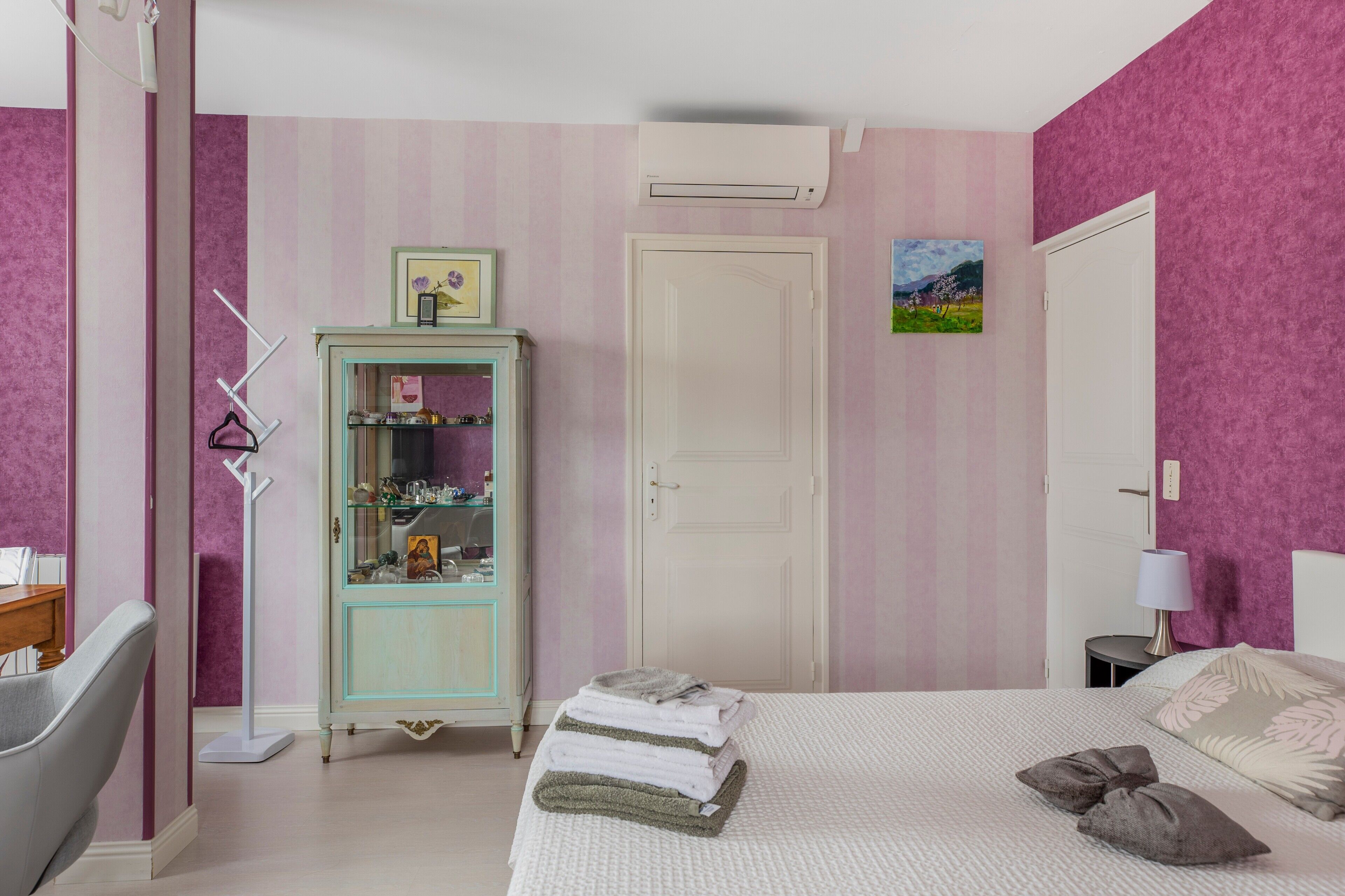 Une chambre à coucher comprenant un lit, une armoire, une porte et un climatiseur fixé au mur.
