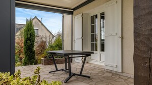 An outdoor patio area with a table and chairs, a door, and a view of a house in the background. - Guest Room - Mon Plaisir (Civray-de-Touraine)