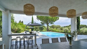 Une terrasse extérieure avec une piscine, un coin repas et des chaises longues.
