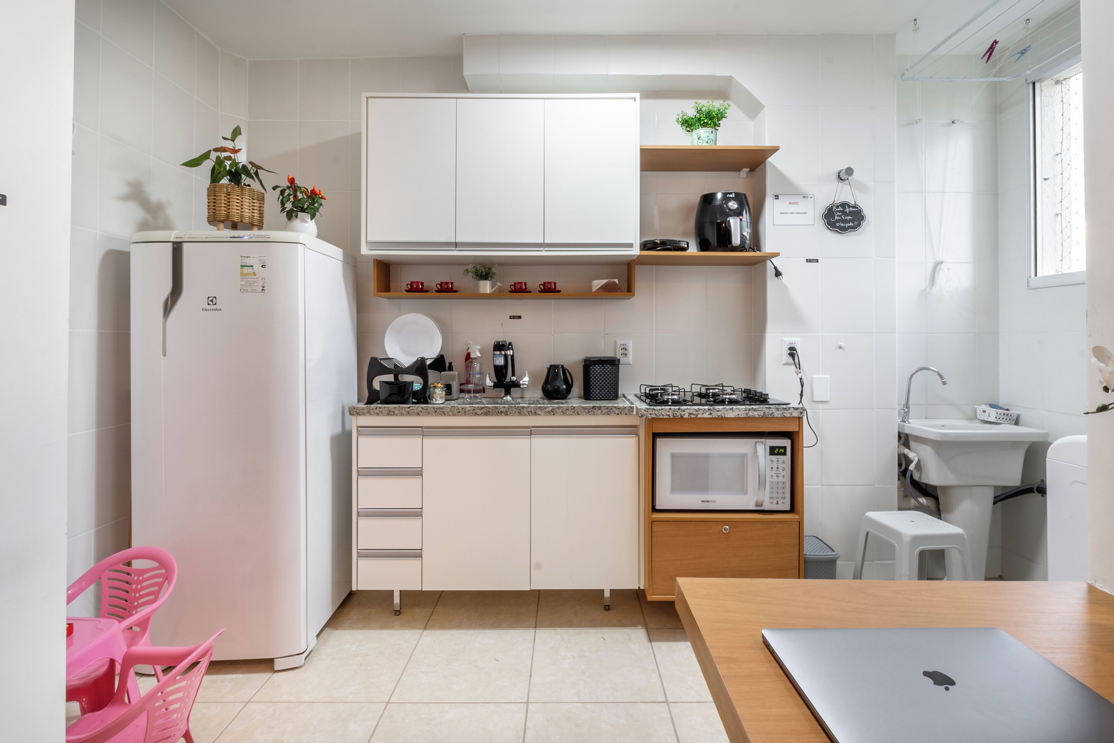 A compact kitchen with white cabinets, a microwave, a sink, and a small dining area with a table and chairs.