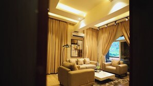 A modern living room with two sofas, a coffee table, and a large window with curtains. - Iri Diplomatic Resorts (Abuja)