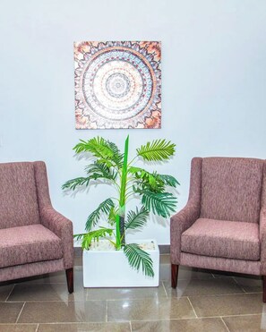 A lobby with two armchairs, a potted plant, and a wall-mounted tapestry. - Iri Diplomatic Resorts (Abuja)