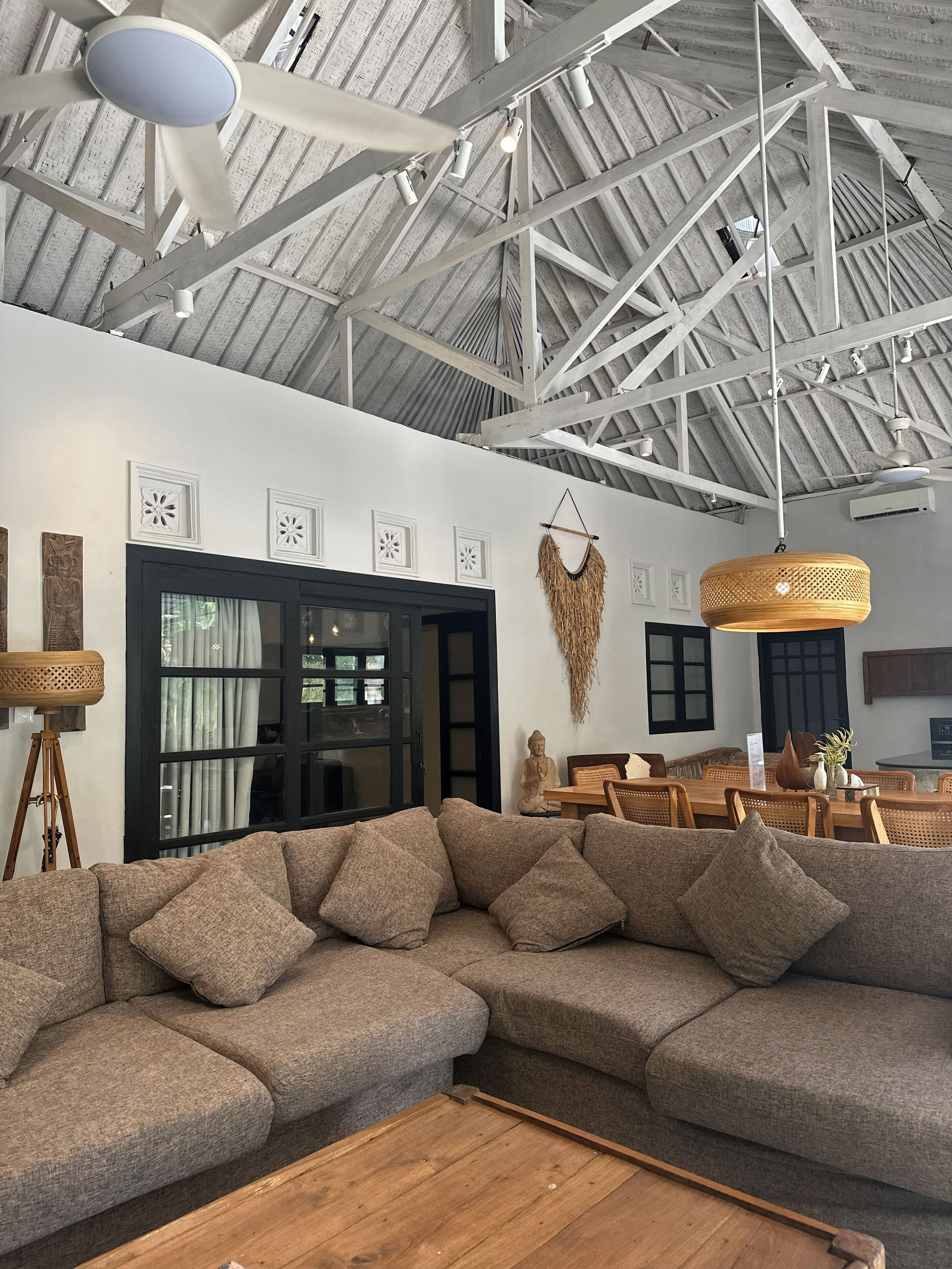 A spacious living room with a large sectional sofa, a wooden coffee table, and a dining area with wooden chairs and a table.