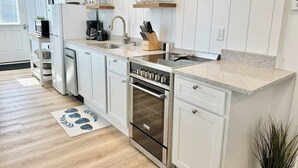 A modern kitchen with white cabinetry, a stainless steel oven, a built-in dishwasher, and a granite countertop. - Private Downtown Bar Harbor Four-Apartment Home (Bar Harbor)