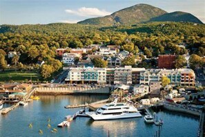 A coastal town with a marina, buildings with balconies, and a hilly backdrop. - Eden in Downtown Bar Harbor (Bar Harbor)