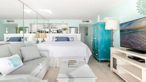 A modern bedroom with a large bed, a sofa, a glass coffee table, a TV, and a kitchen in the background. - Gorgeous Studio with Free Beach Service for 2 at Islander Beach Resort 504 (Fort Walton Beach)