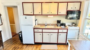Cocina compacta con refrigerador, estufa, microondas y gabinetes de madera.