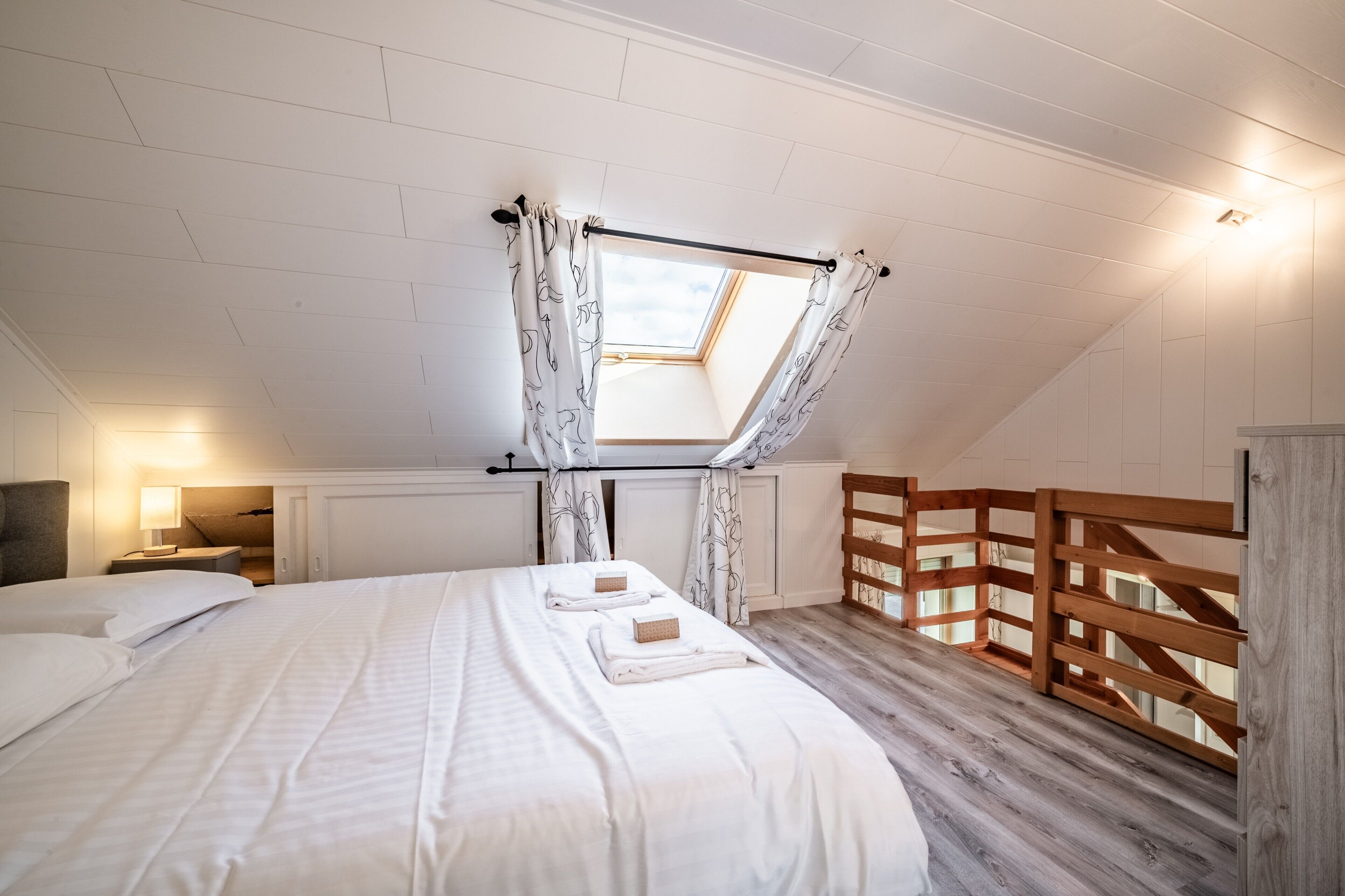 Ein Schlafzimmer mit Oberlicht, einem Holzbettgestell, einem Nachttisch und einer Holzwand.