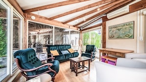 A spacious room with a wooden ceiling, a large sofa, two armchairs, a small table, and a map on the wall.