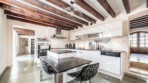 A modern kitchen with a central island, bar stools, and a hanging light fixture.