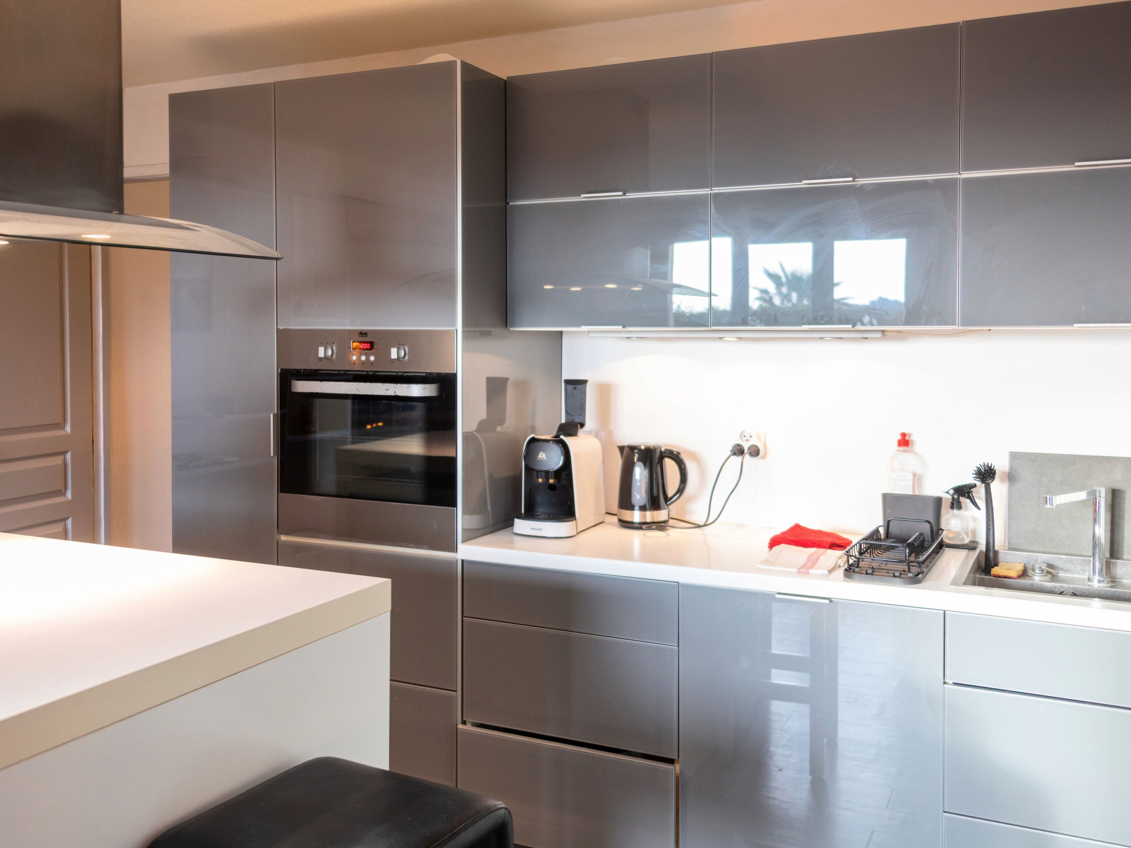 Eine moderne Küche mit Edelstahlgeräten, darunter ein Backofen und eine Kaffeemaschine, und einem klaren, minimalistischen Design.