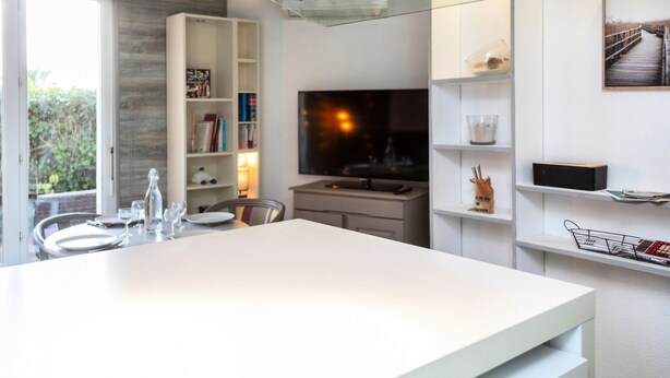 Una cocina moderna con encimera blanca, horno empotrado y salpicadero de vidrio.