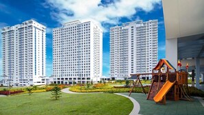 A residential area with three high-rise apartment buildings, a playground with a slide, and well-maintained green lawns. - WIND TAAL TAGAYTAY PHILIPPINES (Tagaytay City)