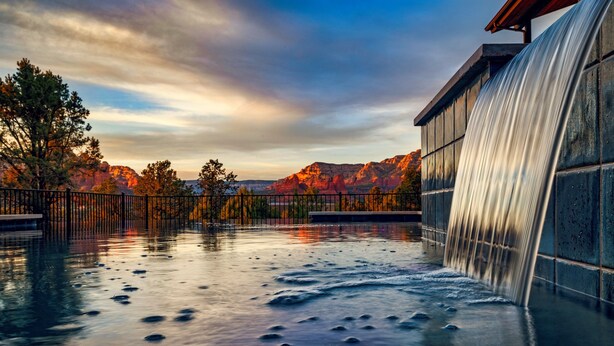 Ein Wasserspiel mit Wasserfall, Pool und Bergblick.