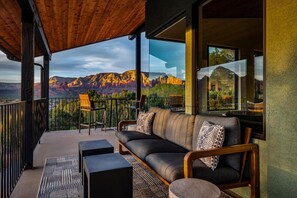 Ein Balkon mit einer Couch, Stühlen und Blick auf die Berge.