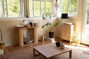 Une pièce avec une table en bois, une plante en pot, un meuble et une fenêtre avec des rideaux.
