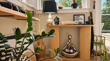 A room with a wooden shelf, a Buddha statue, a lamp, and a sign about rentals and activities.