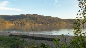 Ein ruhiger See mit einem bewaldeten Hügel im Hintergrund.