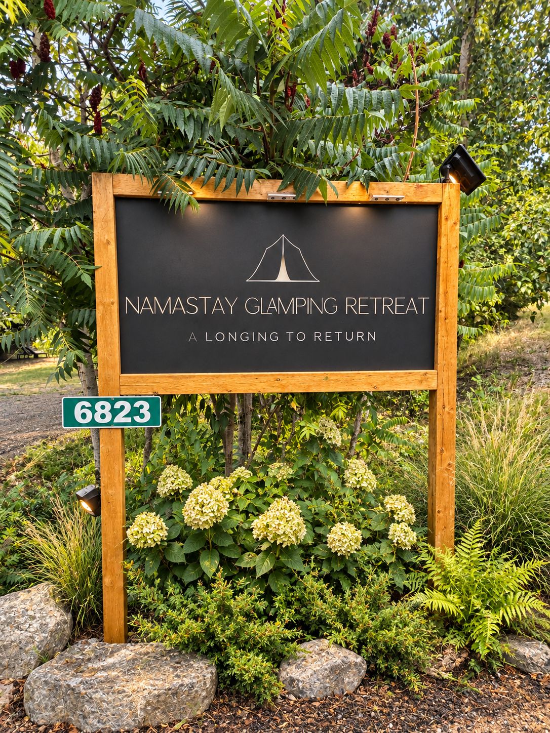 Une enseigne indiquant un lieu de séjour pour les campeurs, avec un logo représentant une tente, le tout entouré de verdure et de rochers.