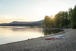 A pebble beach with a clear view of a lake and distant mountains.