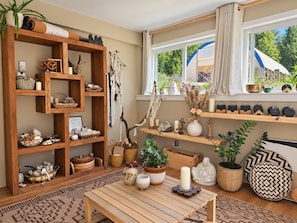 Una habitación acogedora con una estantería de madera, una mesa con velas y una ventana con vistas a la vegetación.
