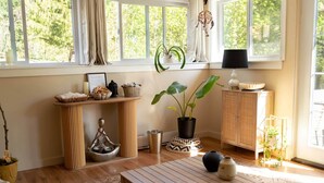 A room with a wooden table, a potted plant, a cabinet, and a window with curtains.