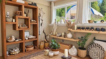 Um quarto acolhedor com uma estante de madeira, uma mesa com velas e uma janela com vista para o verde.