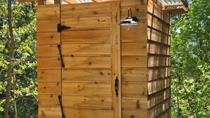 A wooden shed with a corrugated metal roof, a door with a handle, and a small window.