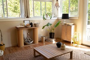 A room with a wooden table, a potted plant, a cabinet, and a window with curtains.