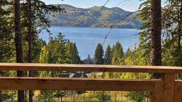 A wooden deck overlooking a lake with trees and distant mountains.