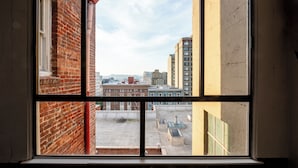 A view through a window with a brick wall on the left, a yellow wall on the right, and a cityscape in the background. - Superhero Hotel (San Francisco)