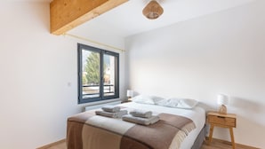 Ein Schlafzimmer mit Bett, Nachttischen, einem Fenster und einer Deckenleuchte.