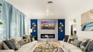 Uma sala de estar moderna com lareira, dois sofás, uma mesa de centro e arte decorativa nas paredes.