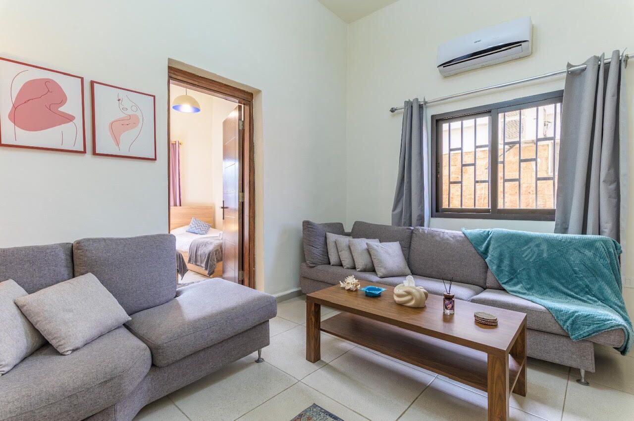 Sala de estar com dois sofás, uma mesa de centro e uma janela com cortinas.