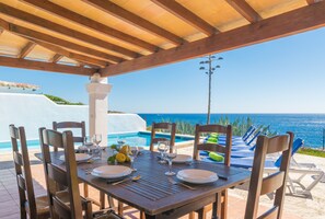 Ein Esstisch, gedeckt für ein Essen, mit Blick auf das Meer.