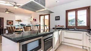 A modern kitchen with a central island, built-in oven, and a window with a view. - Holiday Home 'Amarador' with Private Pool, Wi-Fi and Air Conditioning (Santanyí)