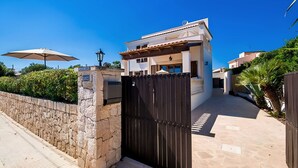 A modern house with a stone wall, a metal gate, and a paved driveway. - Holiday Home 'Amarador' with Private Pool, Wi-Fi and Air Conditioning (Santanyí)