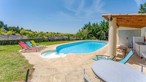 Ein Swimmingpool mit einer eingelassenen Sitzecke, einer Pergola und Gartenmöbeln.